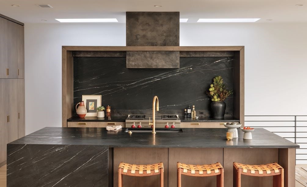 The Wolf 36 Inch Sealed 4 Burner Rangetop and Infrared Griddle installed in a custom wood framed alcove featuring dark marble backsplash with matching kitchen island